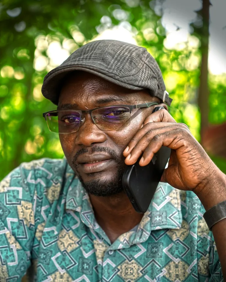 A man in a patterned shirt talks on his phone.